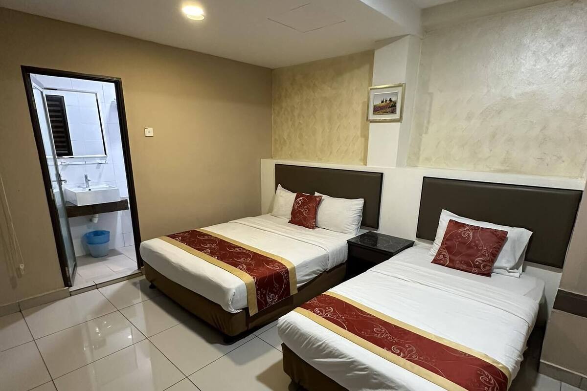 A hotel room with two beds, a bathroom, and a view of the city.