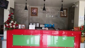 A reception desk with a red and green color scheme, framed certificates, and a wall-mounted sign. - Pornsiri Hotel Sisaket (Sisaket)