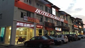 Hotel Global Inn com uma placa visível, uma motocicleta estacionada na frente e vários carros.