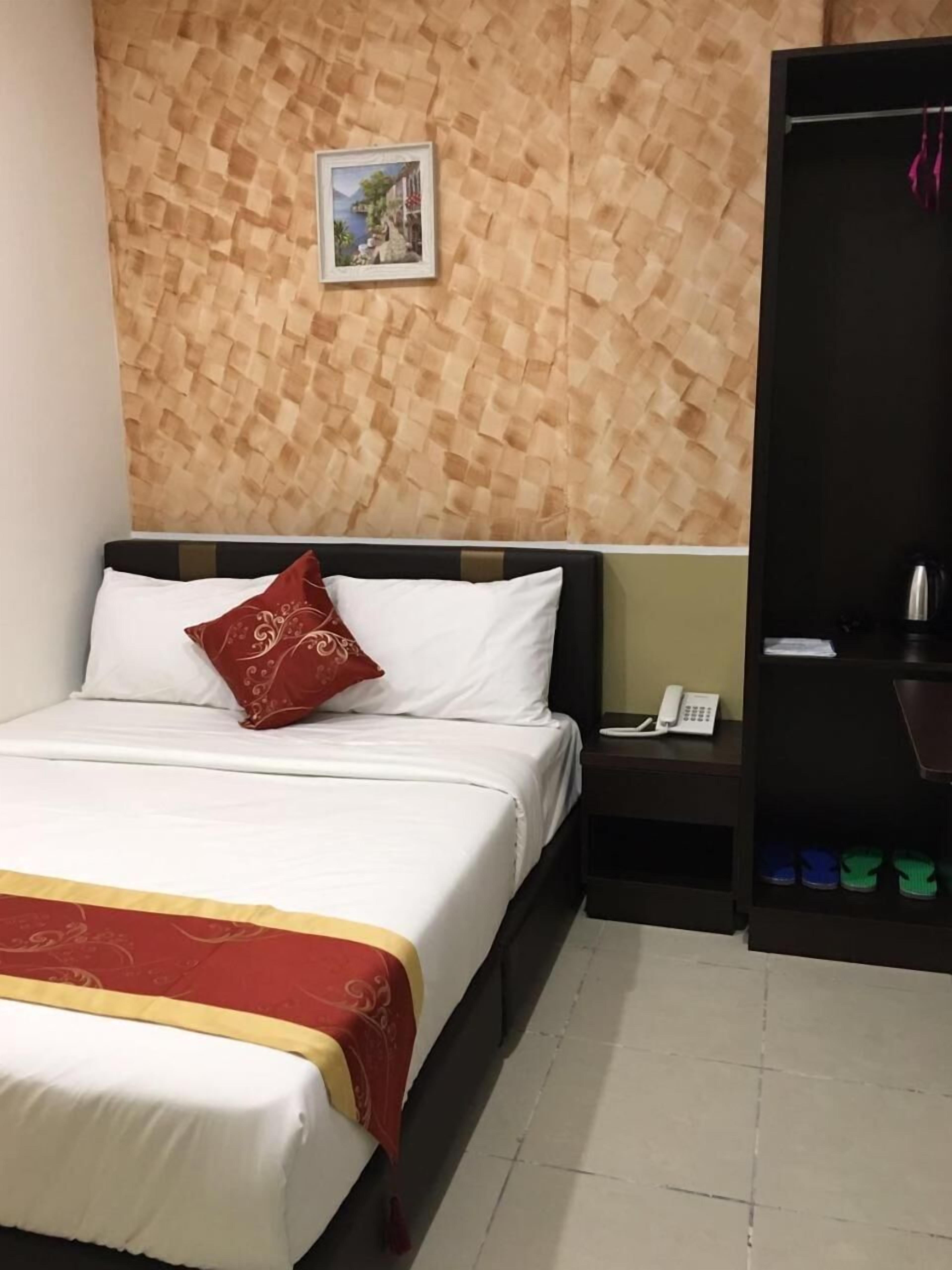 A hotel room with a bed, a nightstand, a telephone, and a wardrobe.