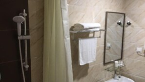 Casa de banho com chuveiro, lavatório, espelho e porta-toalhas.
