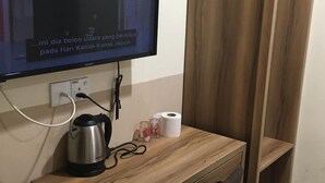 A wooden table with a kettle, a power outlet, and a television mounted on the wall. - SOHO HOTEL (SEMENYIH) SDN. BHD. (Semenyih)