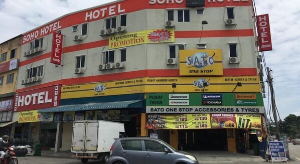 Un hôtel arborant de nombreuses enseignes publicitaires pour promouvoir ses offres et ses services, notamment un point de vente SATO proposant un large choix d'accessoires et de pneus.
