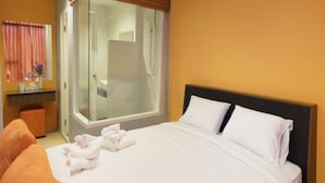 A hotel room with a bed, a bathroom with a glass door, and a window with curtains. - La Casa Pattaya (Pattaya)