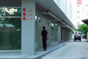 A building with a clear glass facade, a person walking on the sidewalk, and a parked vehicle in the background. - La Casa Pattaya (Pattaya)