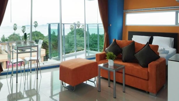 A modern hotel room with a large balcony, a sofa, a small table, and a bed. - La Casa Pattaya (Pattaya)