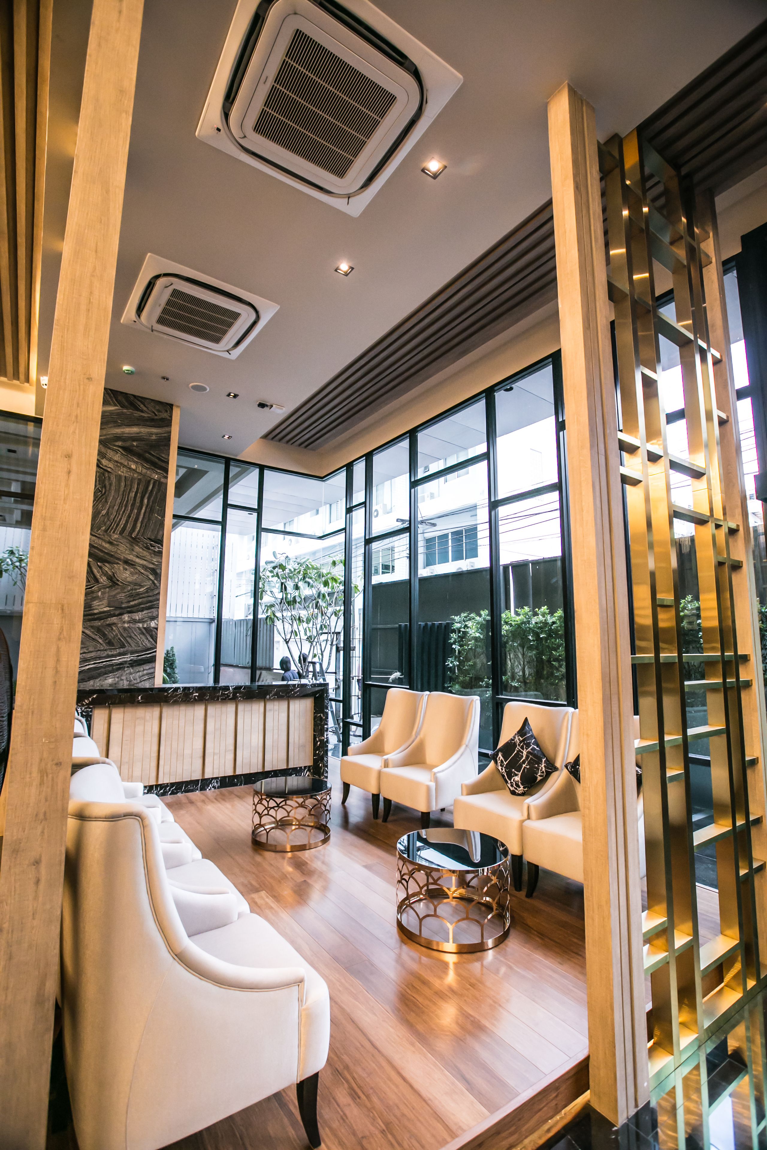 Un vestíbulo moderno con un mostrador de recepción, zona de estar con sofás y sillones, ventanas amplias y conductos de aire acondicionado.