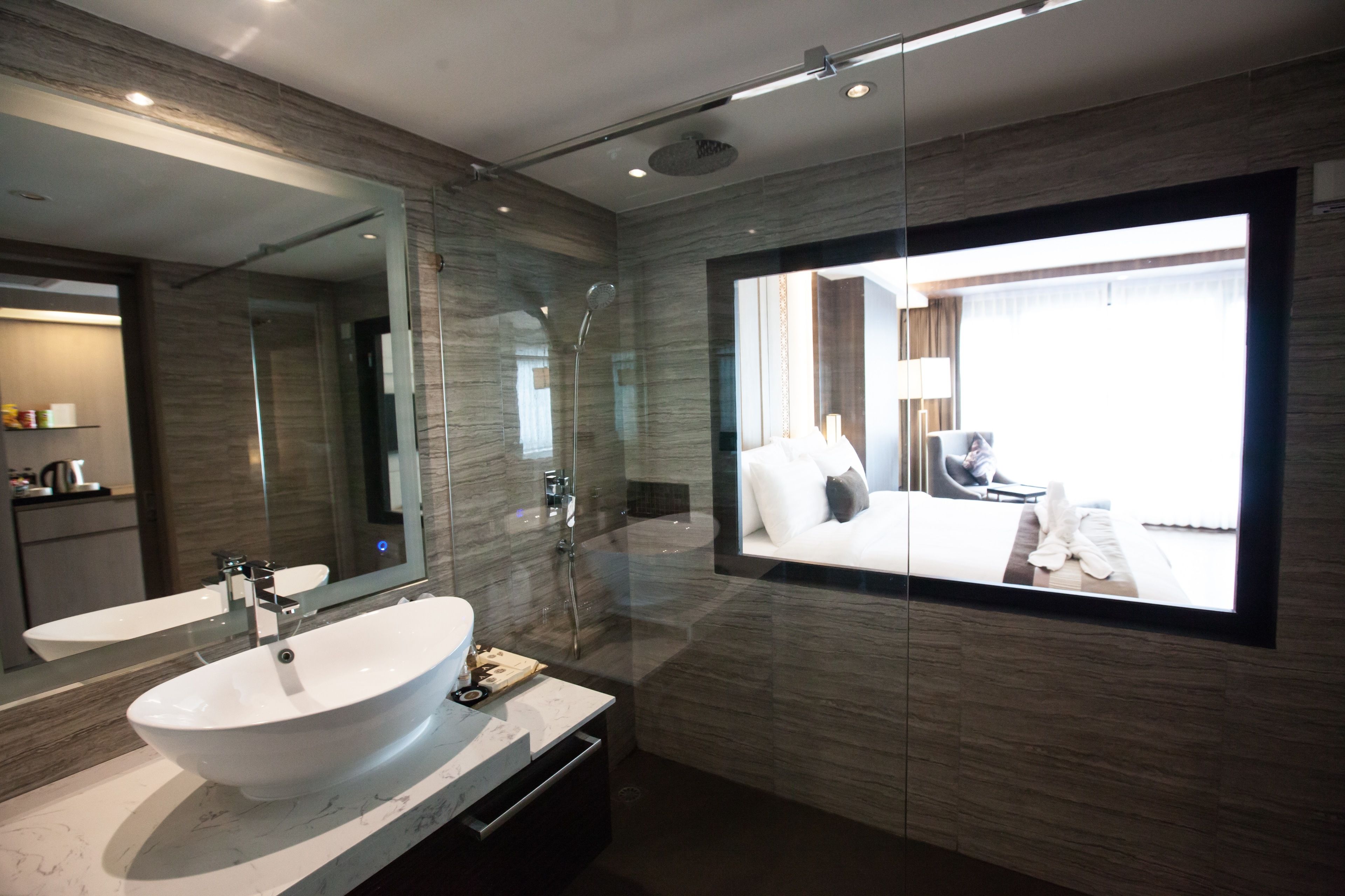 A modern bathroom with a large mirror, a vessel sink, and a shower.