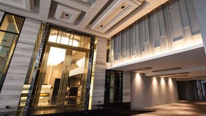 Eine moderne Hotelhalle mit hoher Decke, großen Fenstern und einem imposanten Eingang.