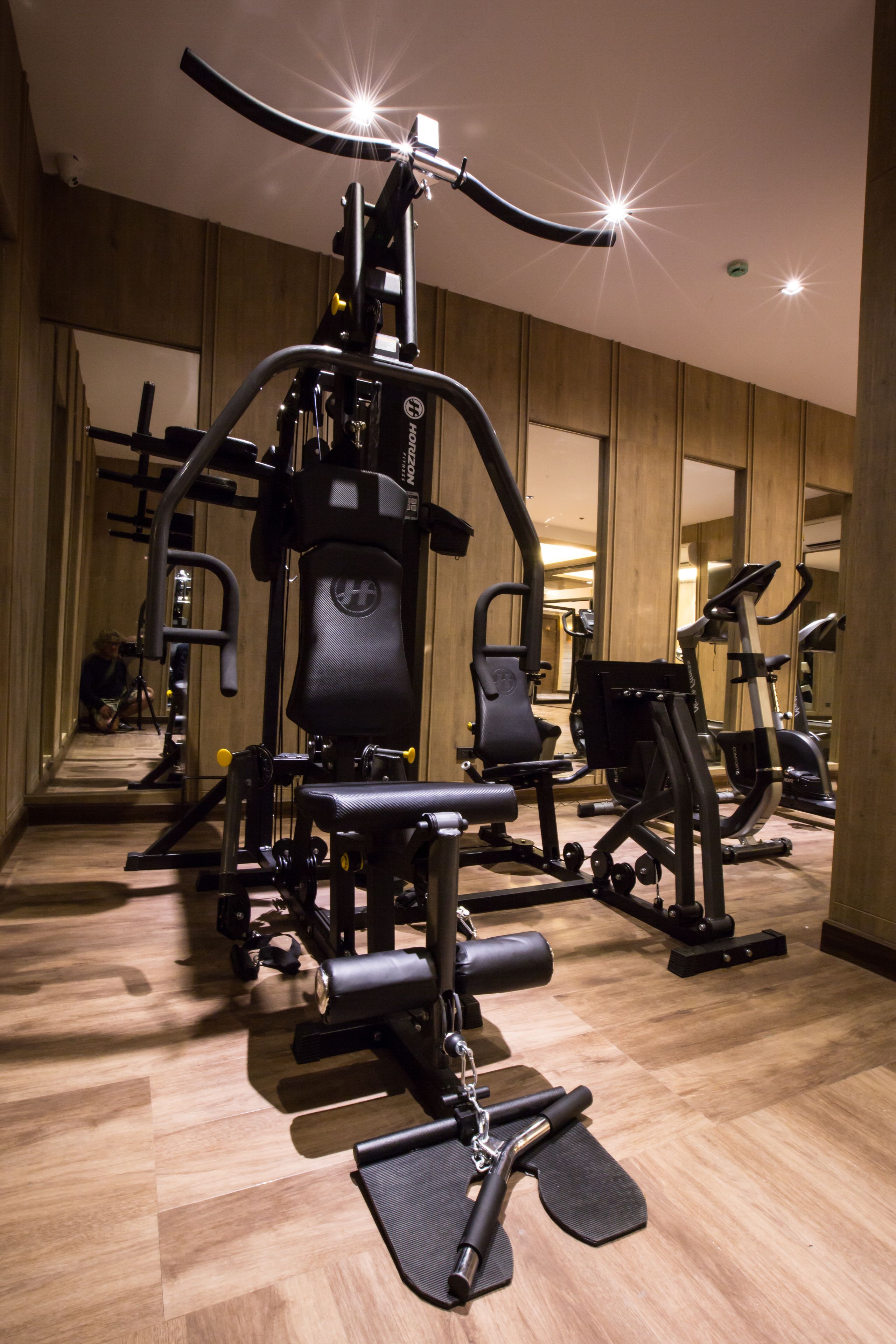 Un gimnasio con equipamiento de ejercicio, paredes de madera y un espejo que refleja el espacio.