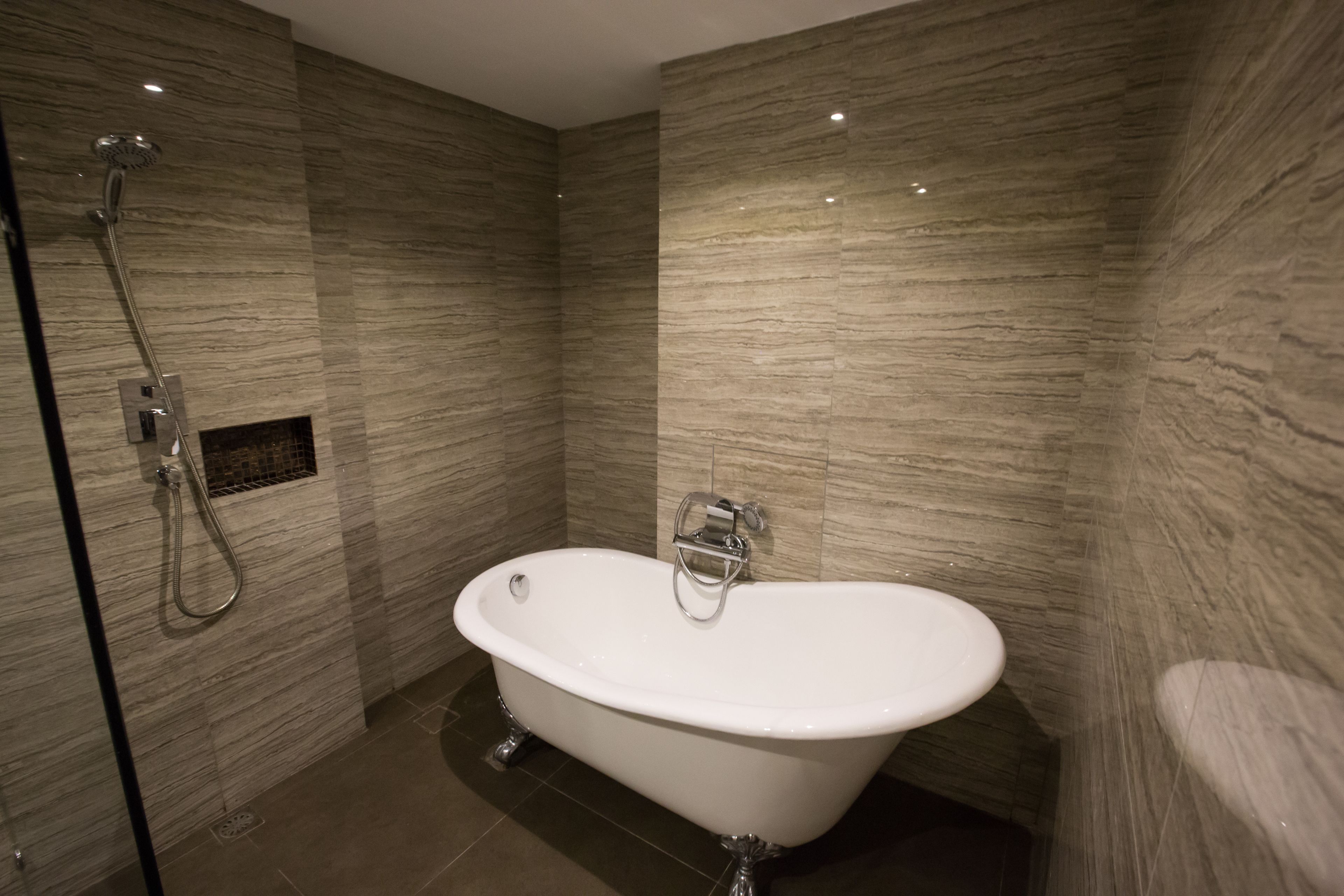 Un baño moderno con una bañera independiente, un cabezal de ducha y un lavamanos montado en la pared.