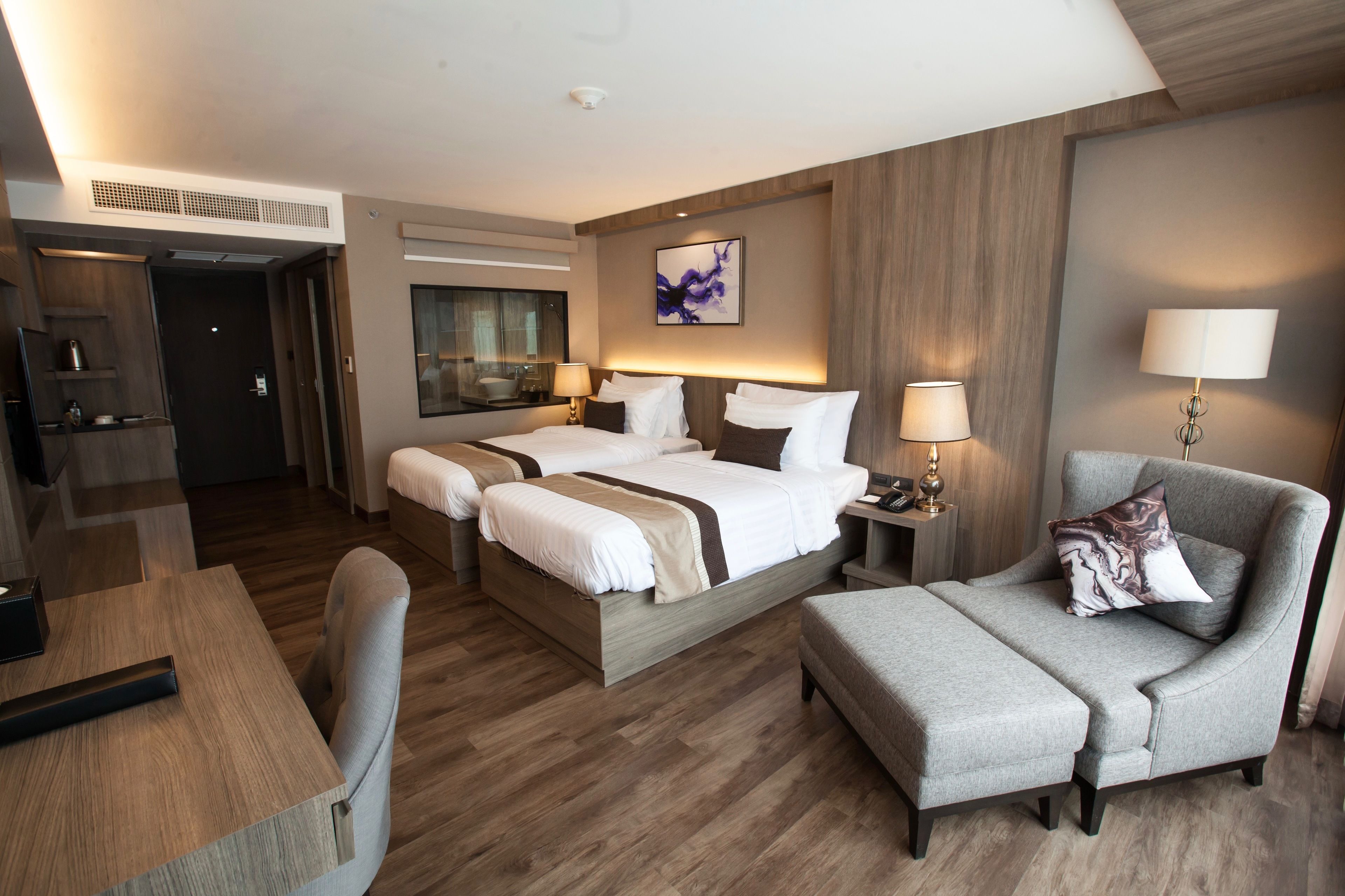 A hotel room with two beds, a desk, a chair, and a sofa.