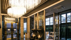 Eine moderne Lobby mit reflektierendem Boden, einer großen Kronleuchter und Sitzbereichen.