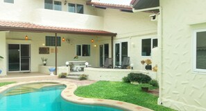 Une maison à deux étages avec une piscine, un patio doté de mobilier d’extérieur et un petit jardin.