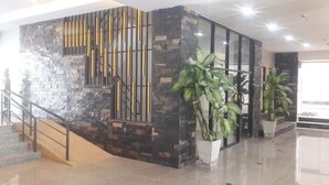Un vestíbulo moderno con una pared de piedra, una escalera y plantas en macetas.