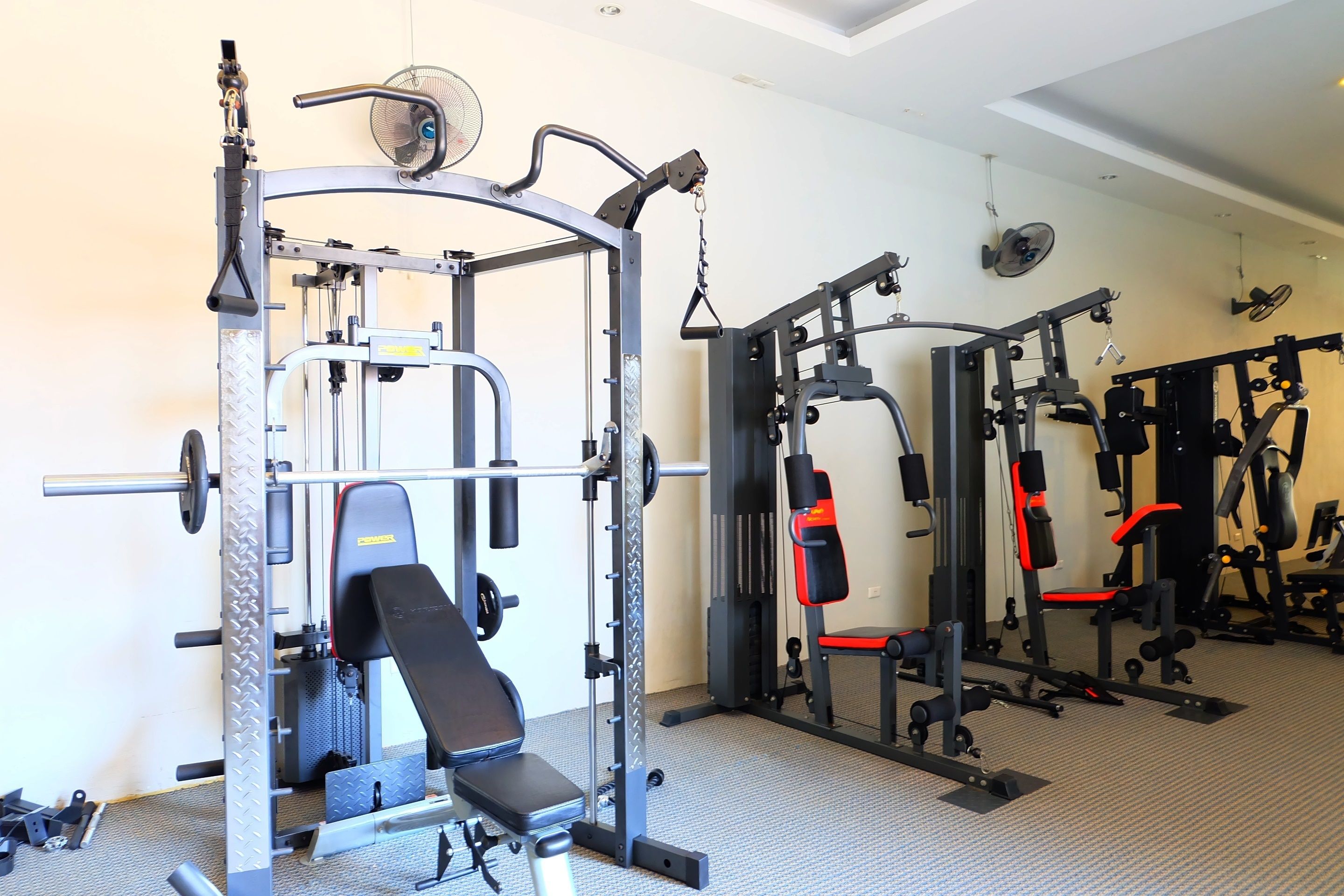 Een fitnessruimte met diverse trainingsapparaten, waaronder een squatrek, bankdrukpers en gewichtsafzetmachines.