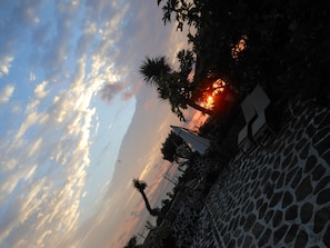 A sunset with clouds, a giraffe enclosure, and a stone pathway.