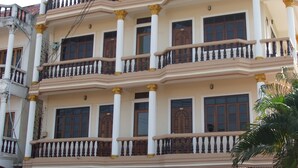 A multi-story building with balconies, a flag, and signs for a hotel and games. - Souvanna Hotel 2 (Vientiane)