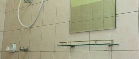 A bathroom with a white sink, a mirror, and a shower with a hose.