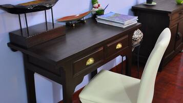 A wooden desk with a white chair, a small plant, and a decorative item on the desk.