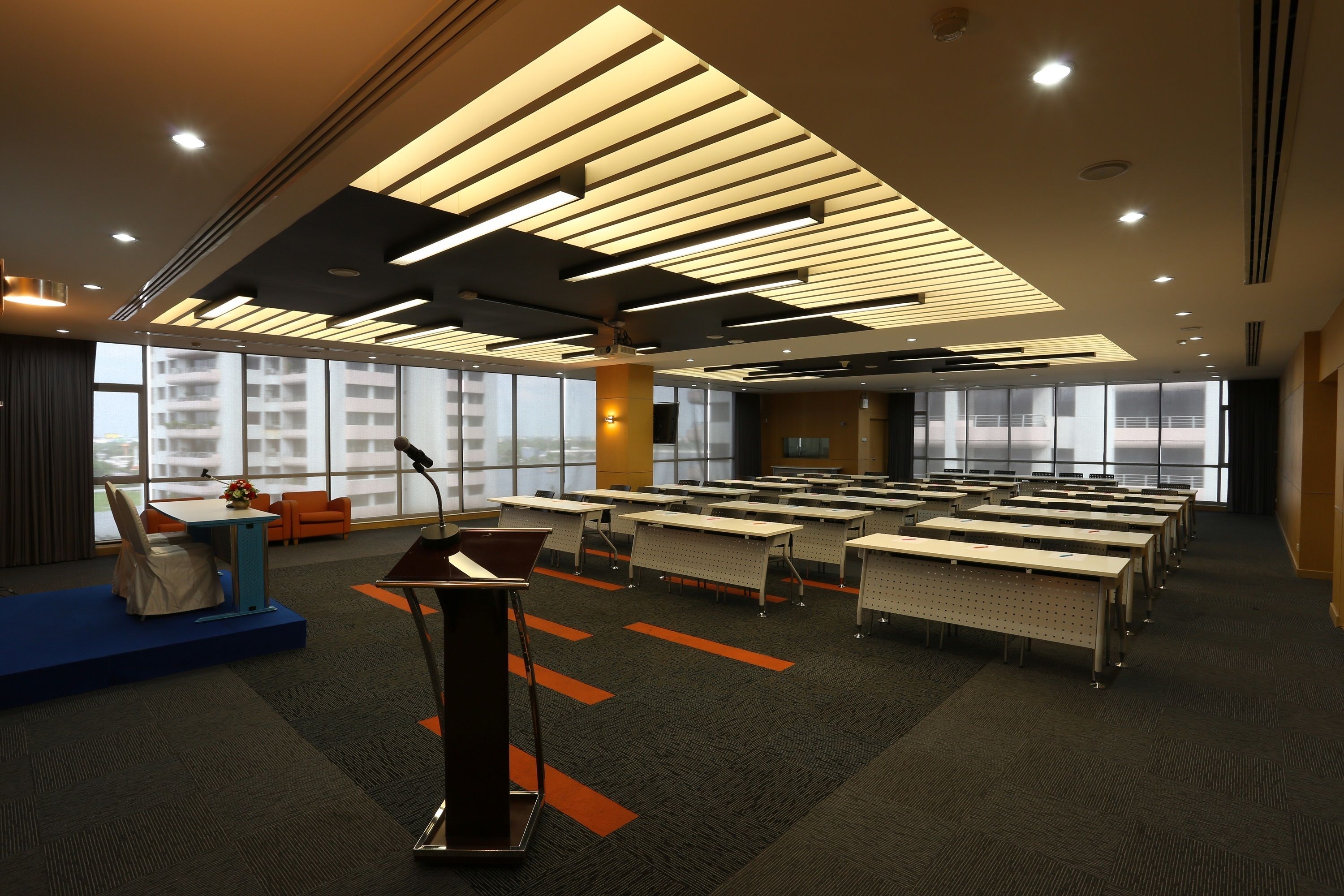 A conference room with tables, chairs, a podium, and large windows.