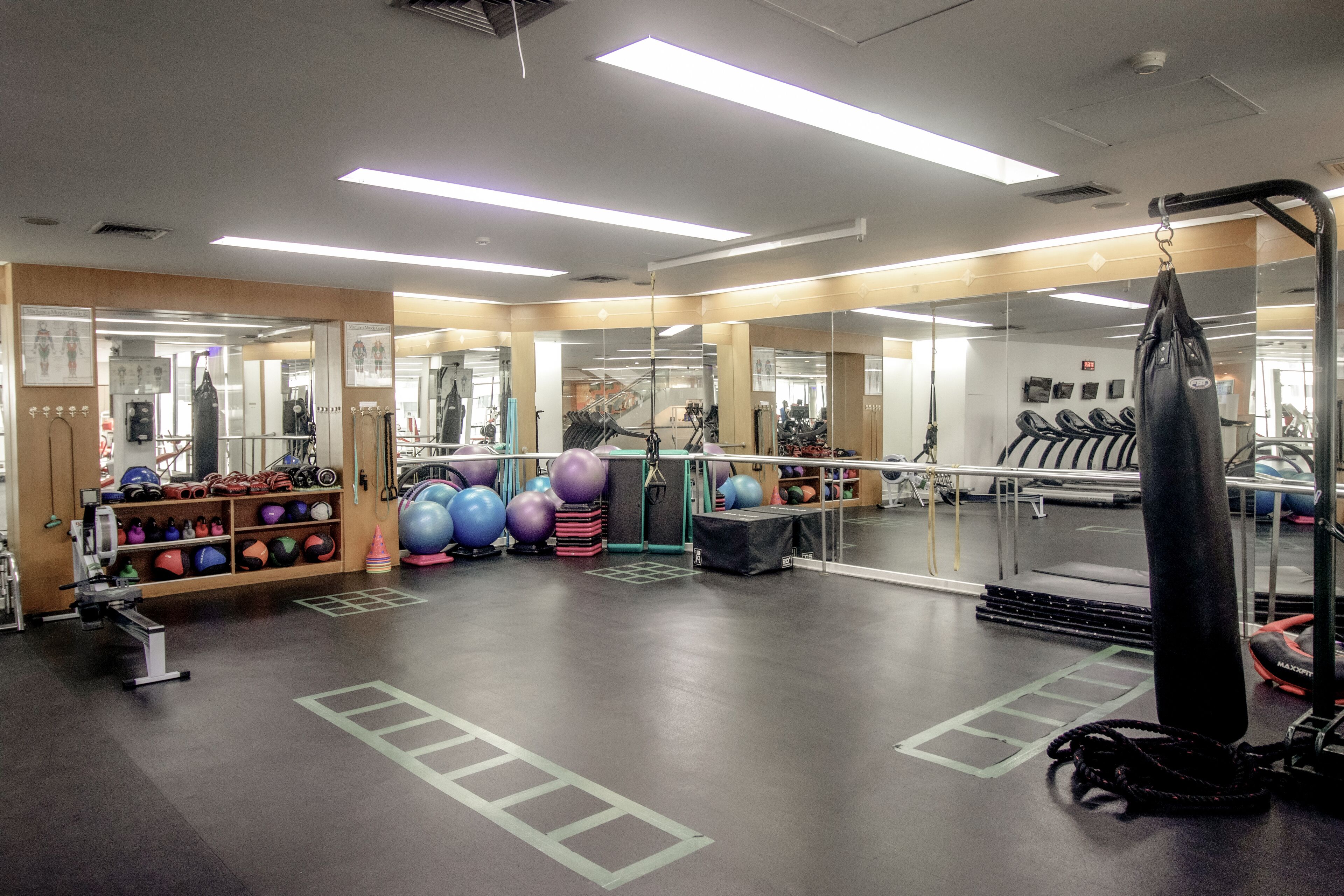 A gym with exercise equipment, mirrors, and a punching bag.