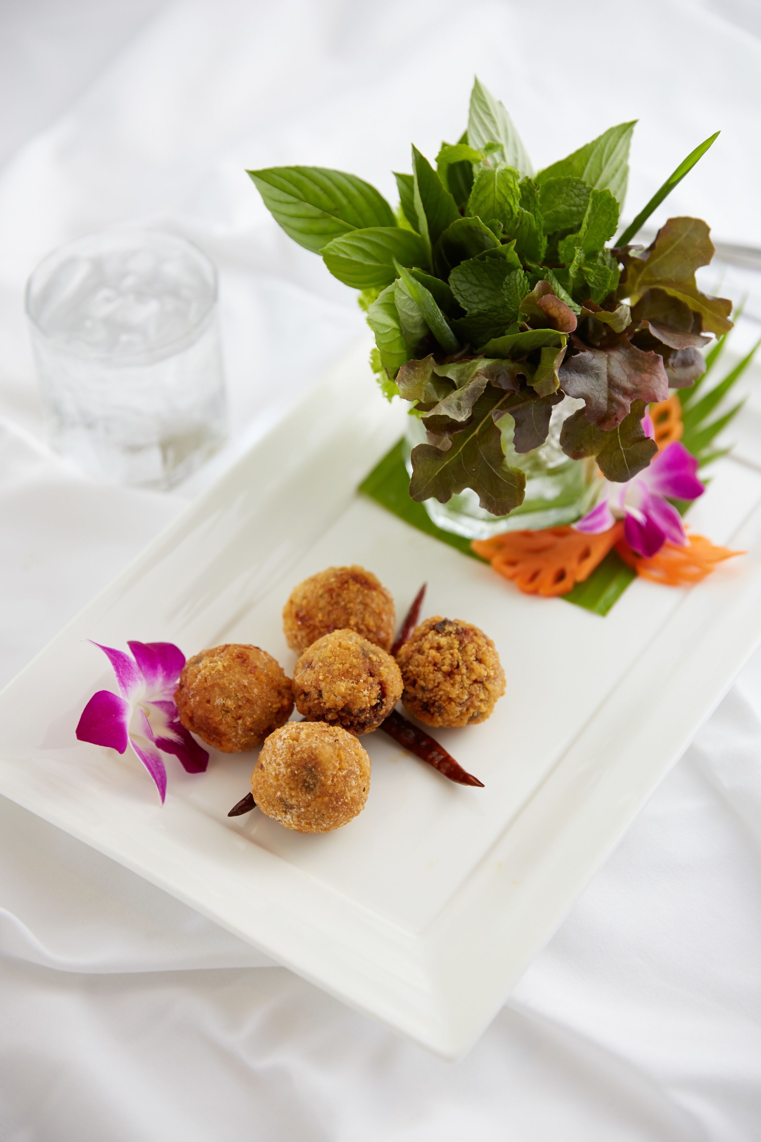 A white rectangular plate with food items and a decorative arrangement of leaves and flowers.