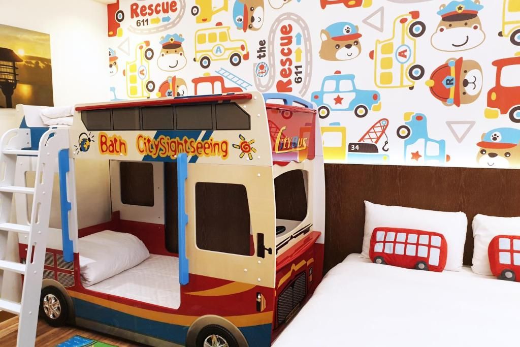 A children's play area with a bus-themed bed and a wall decorated with rescue service vehicles.