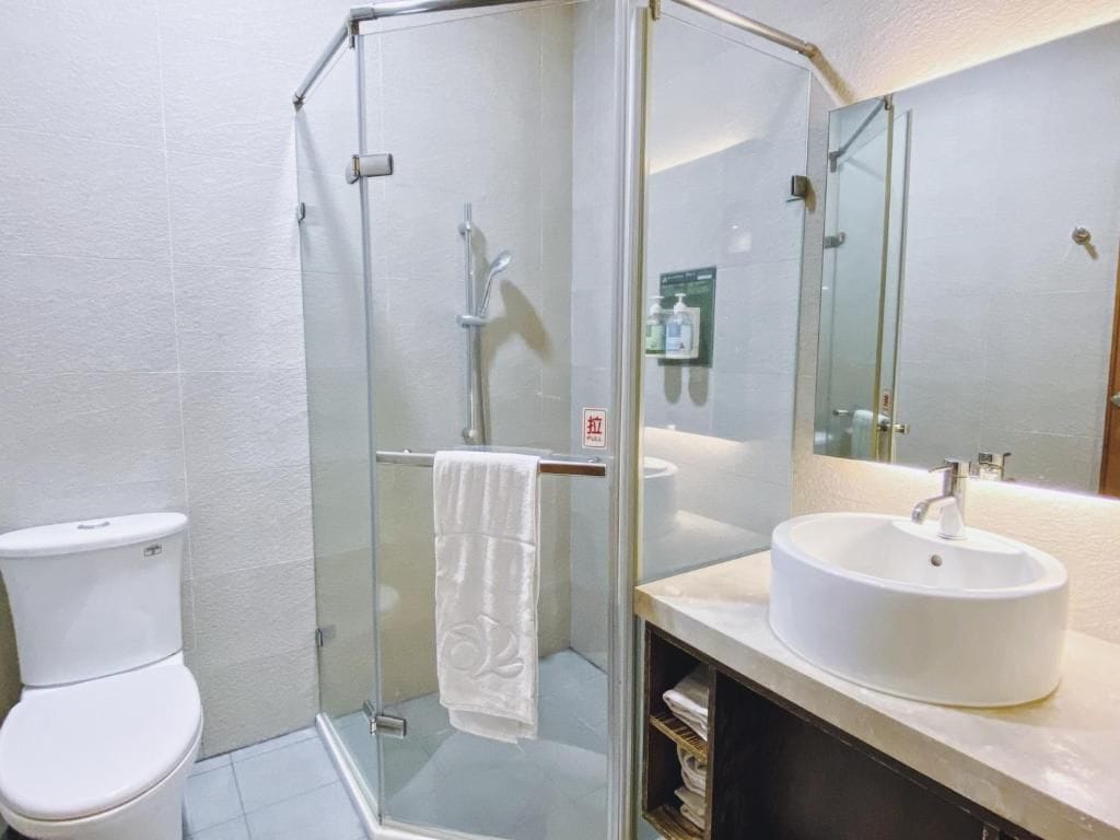 A bathroom with a glass-enclosed shower, a white sink, and a toilet.