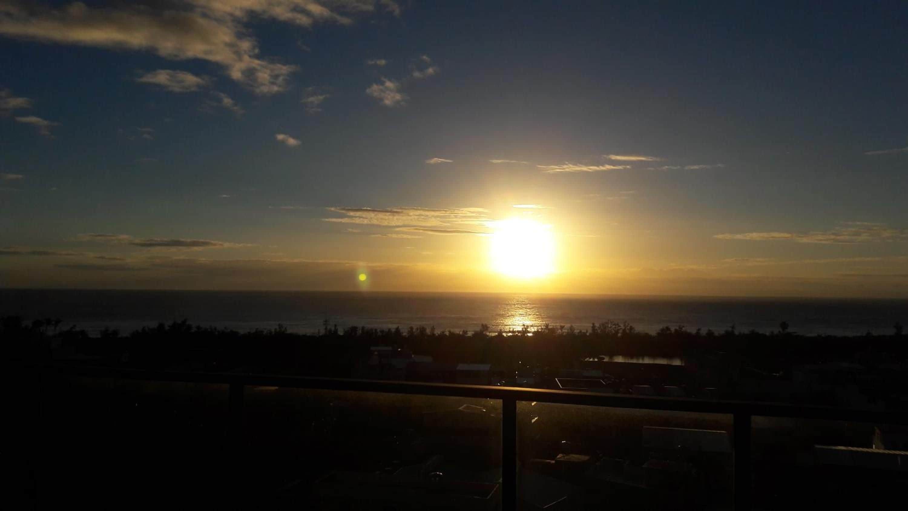 A sunset over a body of water with a distant shoreline.