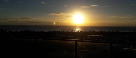 A sunset over a body of water with a distant shoreline.