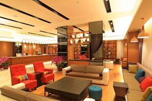 A modern hotel lobby with a reception desk, seating area, and a bookshelf. - Sunrise Hotel & Resort Taimali (Taimali)