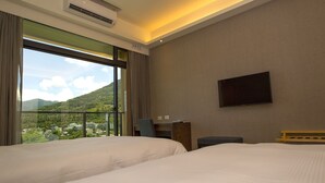 Une chambre d’hôtel avec deux lits, une télévision et une vue sur un paysage montagneux.