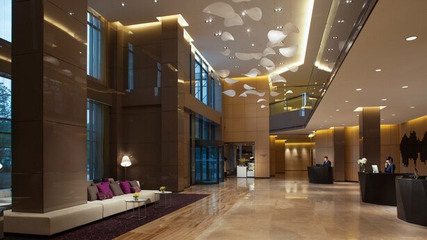 A spacious lobby with a reception desk, seating area, and large windows. - Modena by Fraser Zhuankou Wuhan (Wuhan)