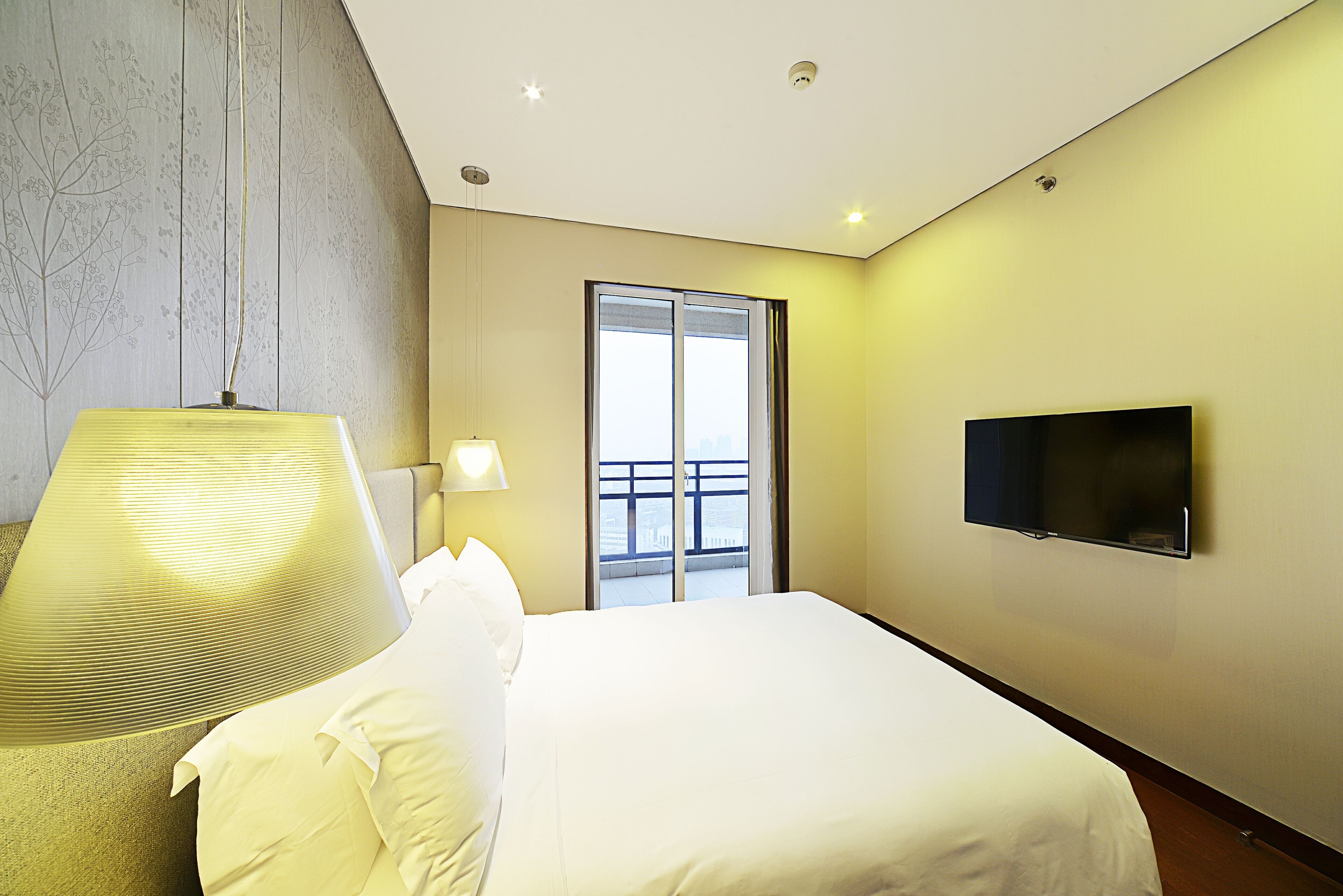 Una habitación de hotel con una cama, un televisor, una lámpara y una ventana con vistas.