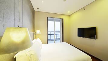 Una habitación de hotel con una cama, un televisor, una lámpara y una ventana con vistas.