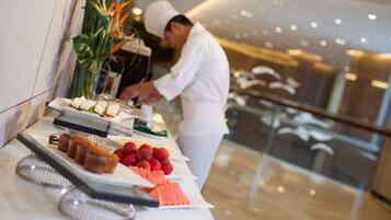 A buffet setup with various food items and a chef preparing food.