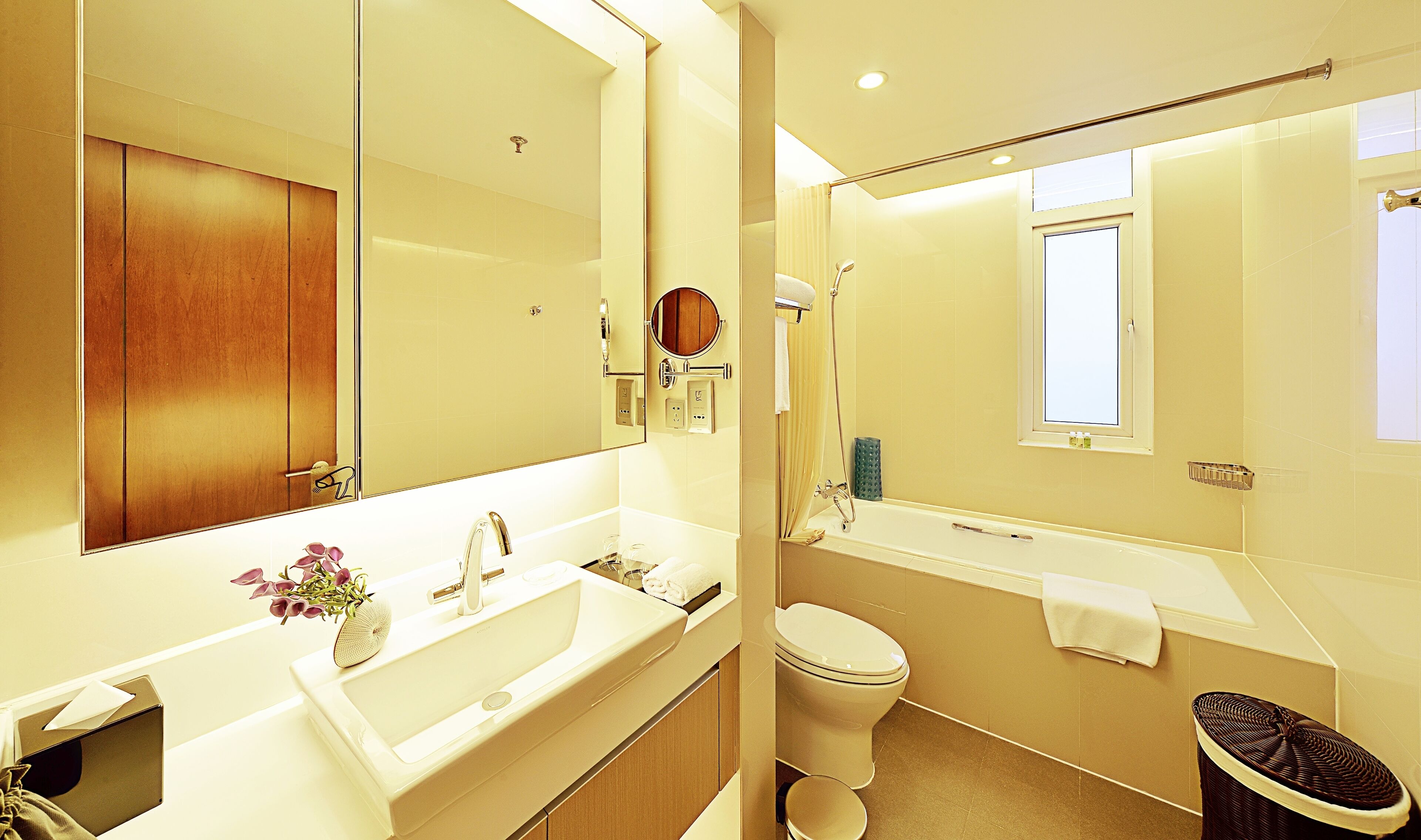 Un baño moderno con un espejo grande, un lavamanos, un inodoro y una zona de ducha.