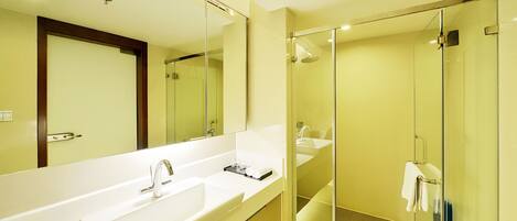 Un baño moderno con un espejo grande, dos lavamanos, una ducha y zona de ducha con mampara de vidrio.