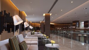 A modern lobby with a seating area, a glass railing, and a decorative wall. - Modena by Fraser Zhuankou Wuhan (Wuhan)