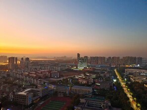 A cityscape at dusk with high-rise buildings, a sports field, and a well-lit road. - Modena by Fraser Zhuankou Wuhan (Wuhan)