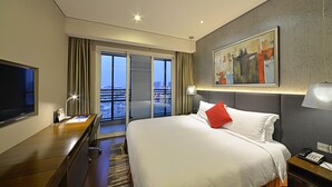 A hotel room with a bed, a desk, a TV, a painting, and a city view. - Modena by Fraser Zhuankou Wuhan (Wuhan)