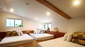 A room with three beds arranged in a U-shape, wooden flooring, and a sloped ceiling with recessed lighting. - Fenchihu Street Hotel (Zhuqi)