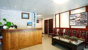 A reception area with a wooden counter, traditional chairs, and a display of brochures.