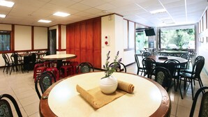 A restaurant with round tables, chairs, and a central decorative vase. - Fenchihu Street Hotel (Zhuqi)