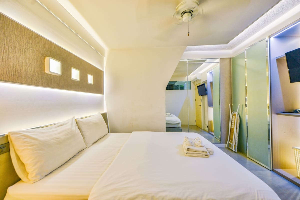Una habitación de hotel con una cama grande, una televisión de pantalla plana y un espejo.