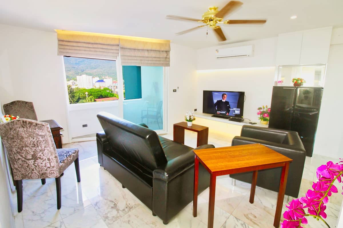 Una sala de estar moderna con un sofá de cuero negro, una mesa de centro de madera y una televisión.