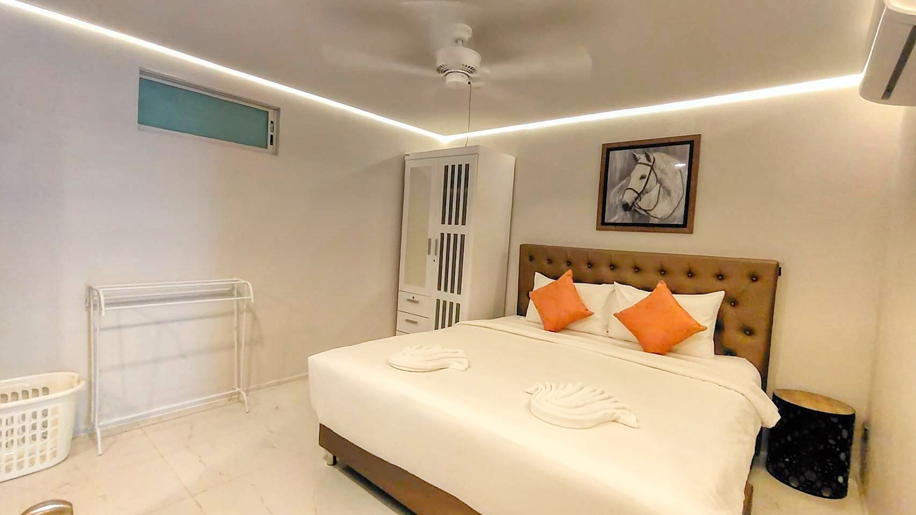 A bedroom with a bed, a radiator, a wardrobe, a ceiling fan, and a framed picture on the wall.