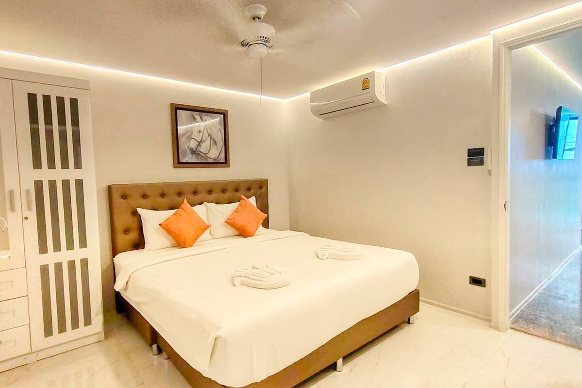 Habitación de hotel con una cama grande, un armario, un equipo de aire acondicionado y un cuadro en la pared.