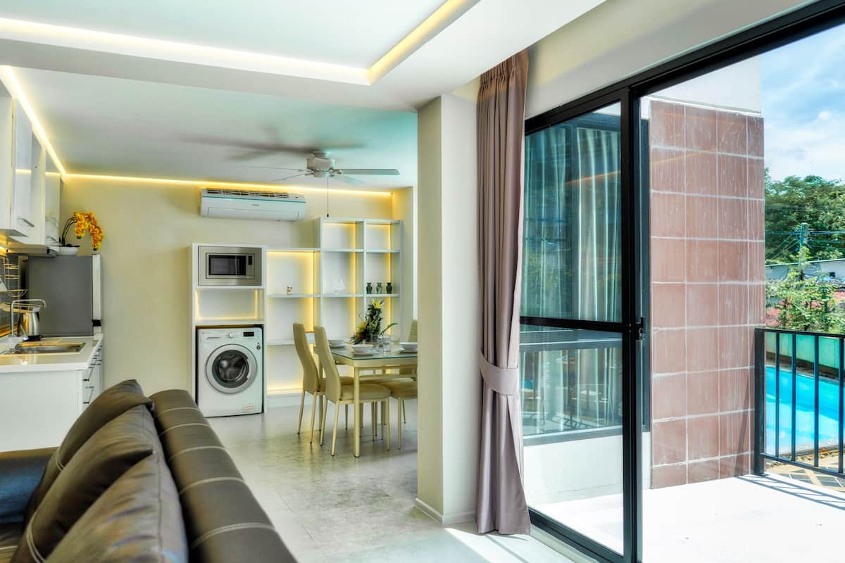 Un espacio habitable moderno con comedor, cocina y un balcón con piscina.